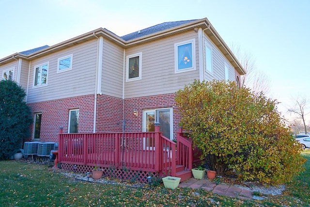 back of house with central AC unit, a deck, and a yard