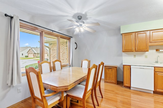 dining space with a textured ceiling, ceiling fan, light wood-type flooring, and sink