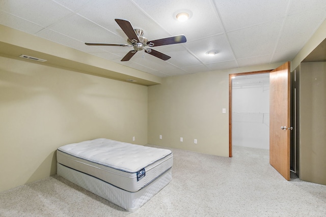 bedroom with ceiling fan, a drop ceiling, a walk in closet, and a closet