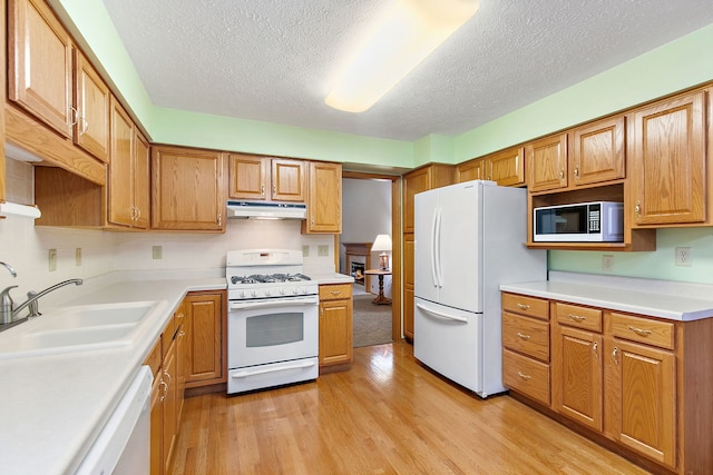 kitchen with a textured ceiling, white appliances, light hardwood / wood-style floors, and sink