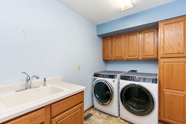 clothes washing area featuring washer and dryer, sink, cabinets, and a textured ceiling