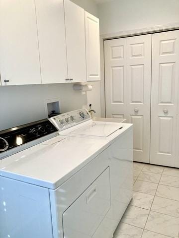 clothes washing area with separate washer and dryer and cabinets