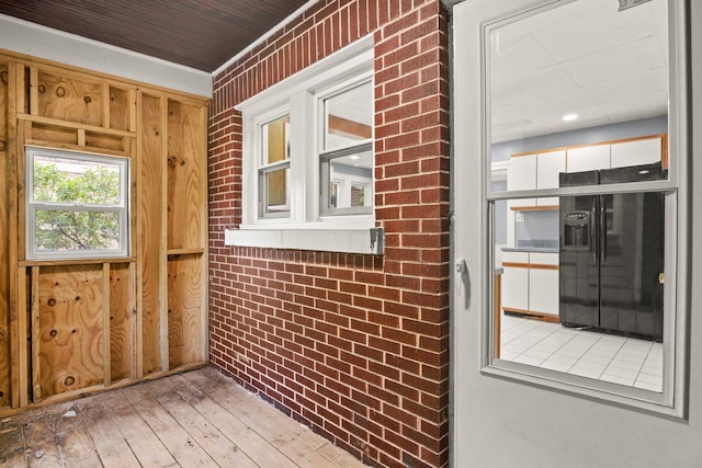 interior space with brick wall, wood walls, and light wood-type flooring