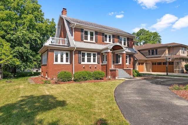 view of front of home with a garage, a balcony, and a front yard