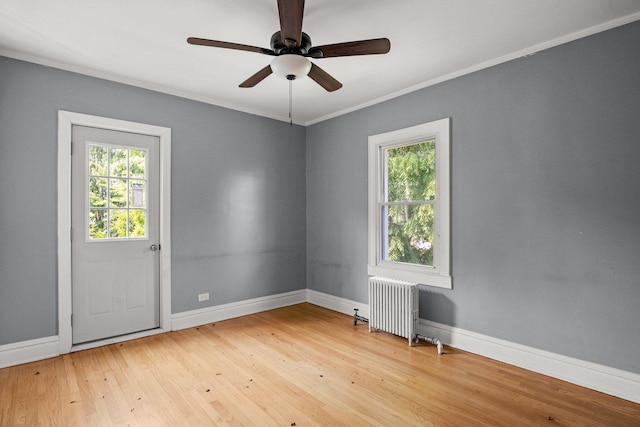 empty room featuring radiator, hardwood / wood-style floors, ceiling fan, and crown molding