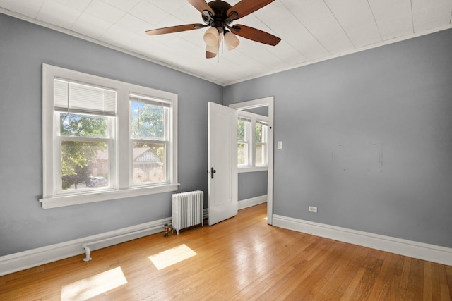 unfurnished room with ceiling fan, light hardwood / wood-style floors, and radiator