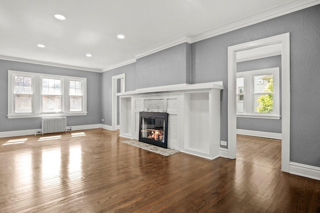 unfurnished living room featuring ornamental molding, radiator heating unit, hardwood / wood-style floors, and a fireplace