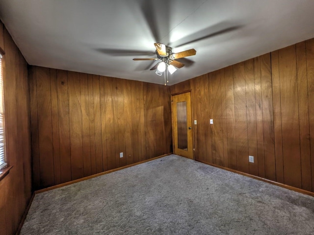 carpeted empty room featuring ceiling fan and wood walls