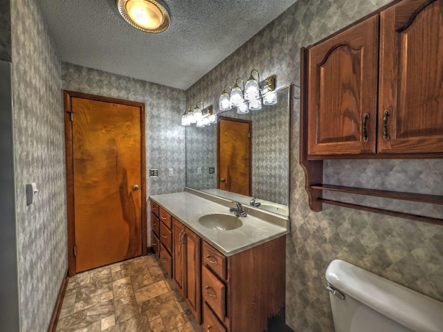 bathroom with vanity, a textured ceiling, and toilet