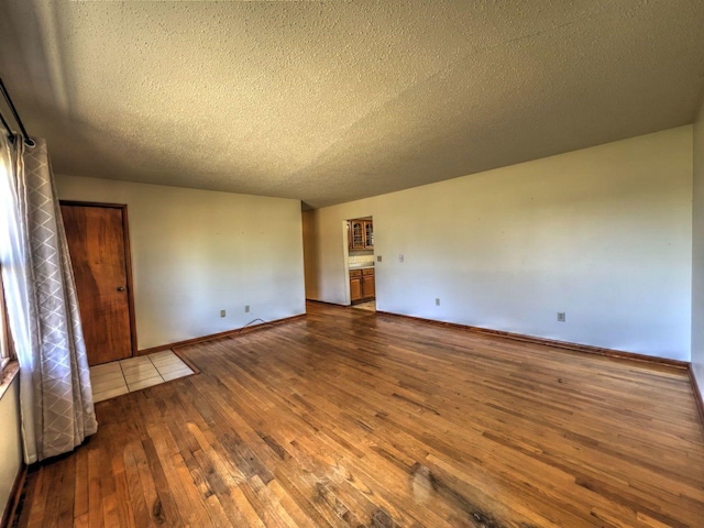 unfurnished room with wood-type flooring and a textured ceiling