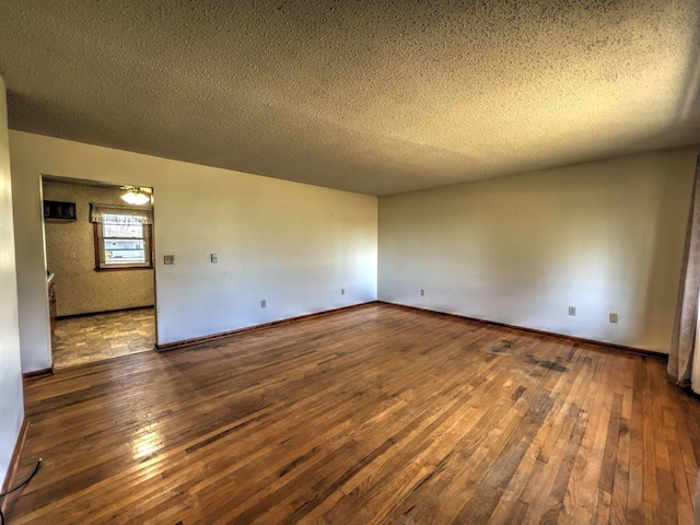 spare room with a textured ceiling and dark wood-type flooring