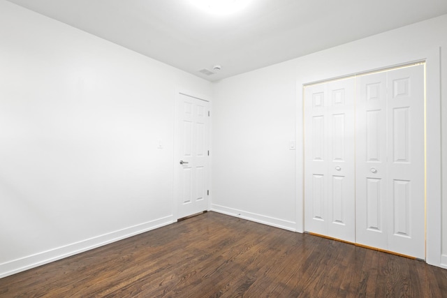 unfurnished bedroom with dark wood-type flooring and a closet