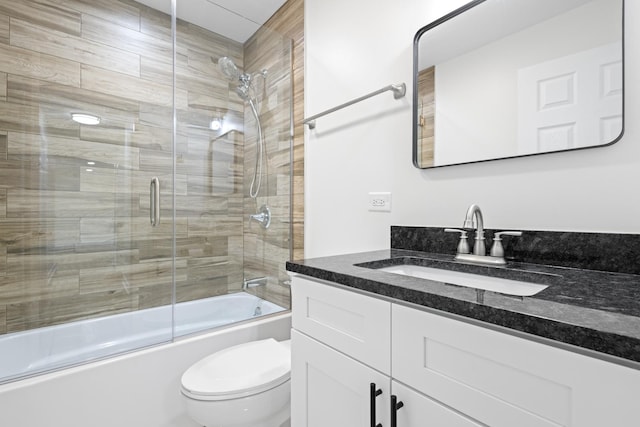 full bathroom with combined bath / shower with glass door, vanity, and toilet