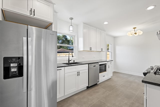 kitchen featuring backsplash, stainless steel appliances, sink, pendant lighting, and white cabinetry