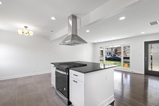 kitchen featuring wall chimney exhaust hood, gas stove, wood-type flooring, dark stone countertops, and white cabinets