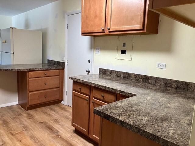 kitchen with a peninsula, dark countertops, and brown cabinets