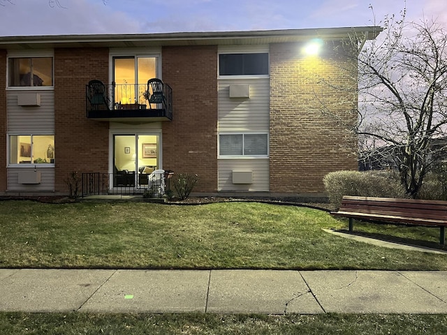 view of front of home with a balcony and a lawn