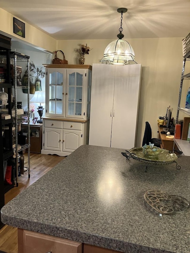 kitchen with white cabinetry, light hardwood / wood-style flooring, and hanging light fixtures