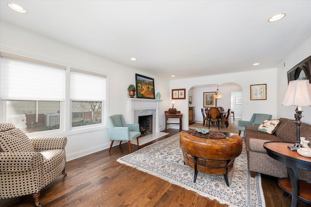 living room with a high end fireplace, dark hardwood / wood-style flooring, and ornamental molding