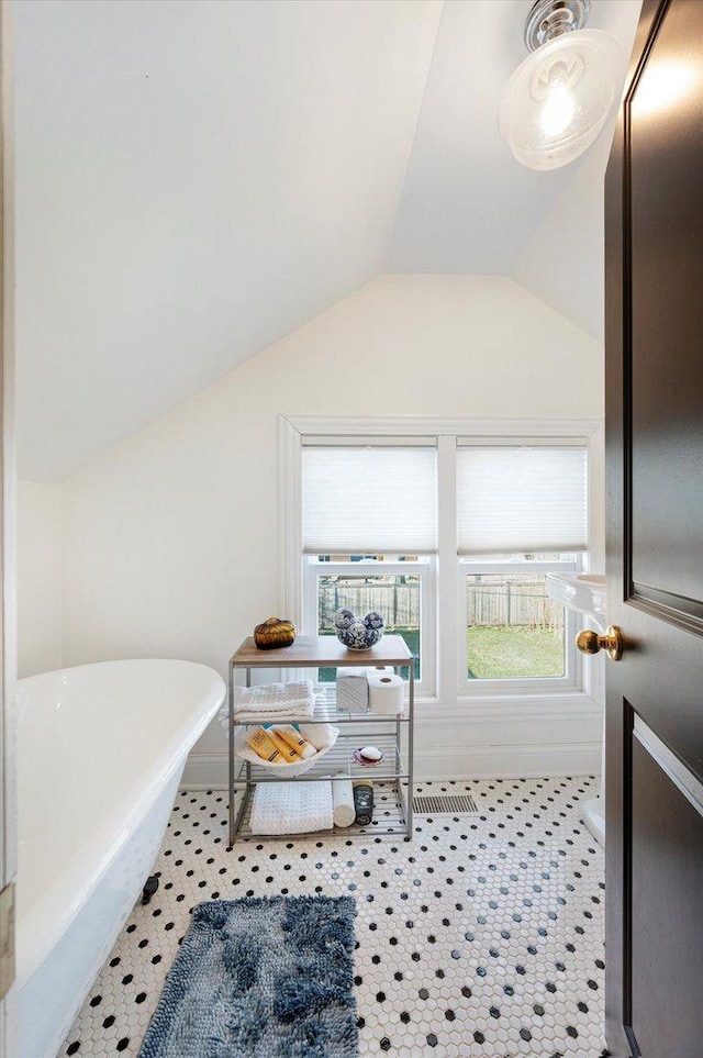 bathroom featuring tile patterned flooring, a washtub, and vaulted ceiling