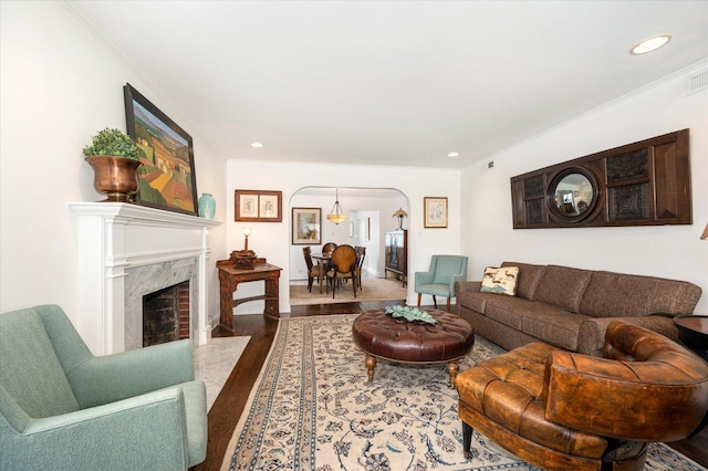 living room featuring wood-type flooring, ornamental molding, and a fireplace