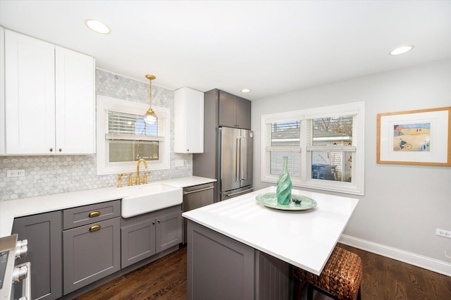 kitchen with hanging light fixtures, gray cabinetry, sink, and a healthy amount of sunlight