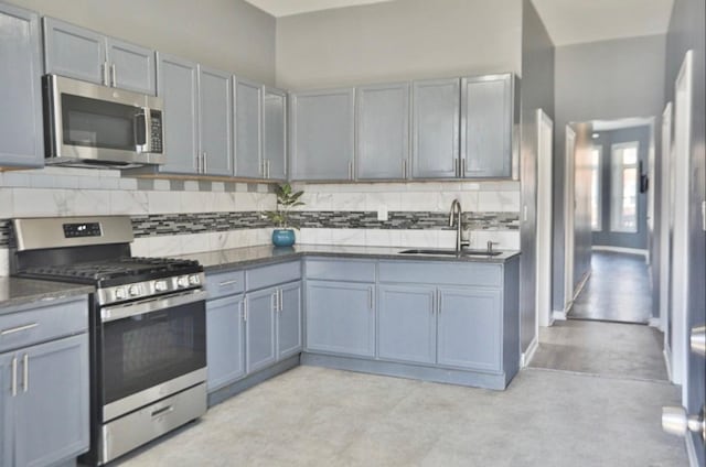 kitchen with appliances with stainless steel finishes, backsplash, gray cabinetry, and sink