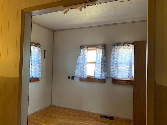 empty room with light hardwood / wood-style floors and wooden walls