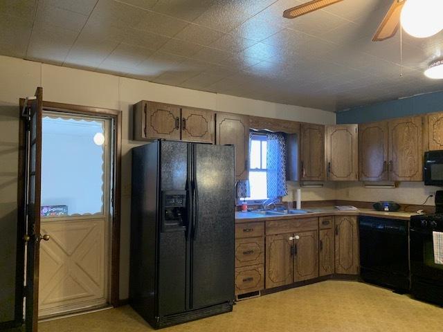 kitchen featuring sink, light colored carpet, ceiling fan, and black appliances