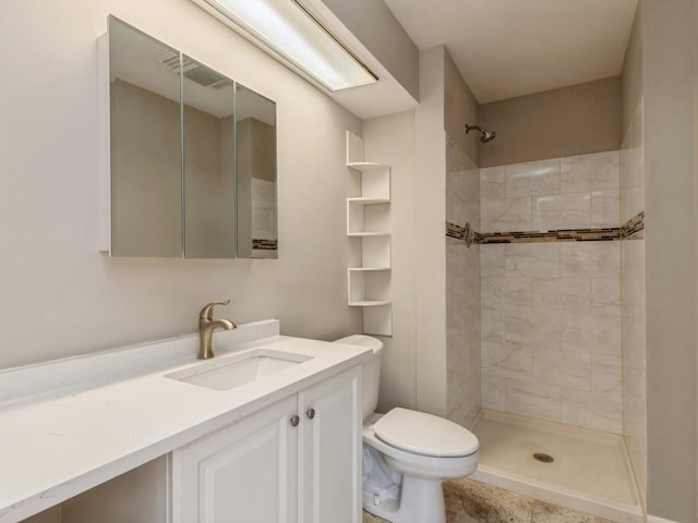 bathroom featuring toilet, vanity, and tiled shower