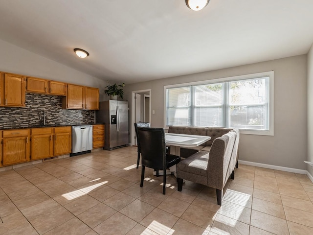 dining area featuring sink, light tile patterned flooring, and vaulted ceiling