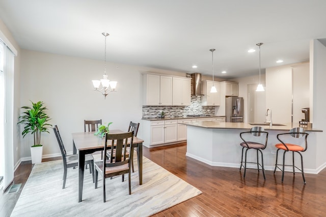 kitchen featuring sink, stainless steel appliances, wall chimney range hood, and pendant lighting