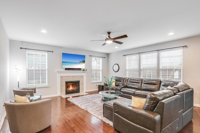 living room with a tiled fireplace, dark hardwood / wood-style flooring, and ceiling fan