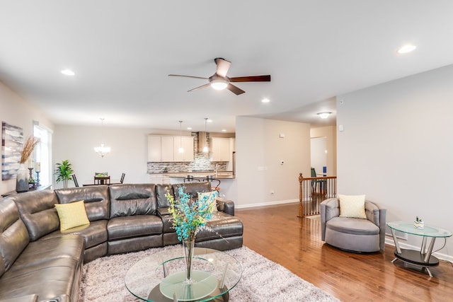 living room with ceiling fan with notable chandelier and light wood-type flooring