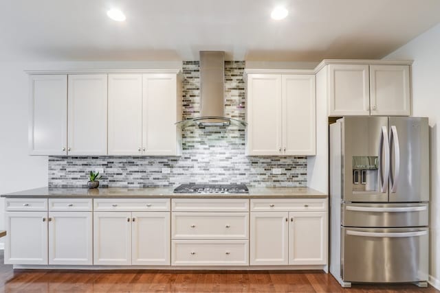 kitchen featuring appliances with stainless steel finishes, white cabinetry, and wall chimney range hood