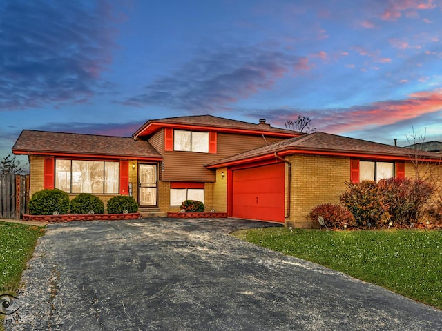 split level home featuring a lawn and a garage