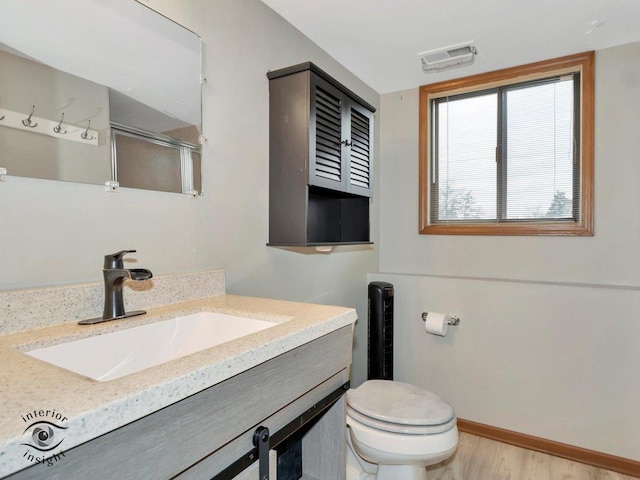 bathroom featuring hardwood / wood-style floors, a shower with door, toilet, and vanity