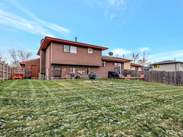 rear view of house featuring central AC unit and a yard