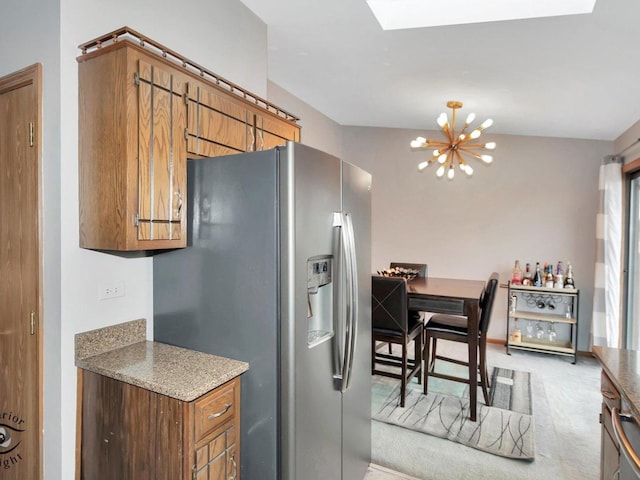 kitchen with stone counters, stainless steel fridge with ice dispenser, light carpet, and a chandelier