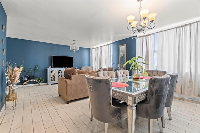 dining space with light hardwood / wood-style floors and an inviting chandelier