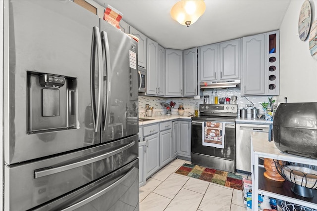 kitchen with gray cabinets, light tile patterned flooring, appliances with stainless steel finishes, and tasteful backsplash