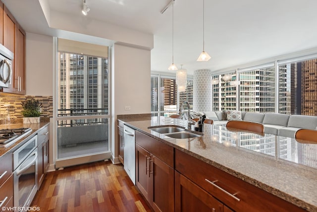 kitchen with backsplash, hanging light fixtures, sink, appliances with stainless steel finishes, and light stone counters