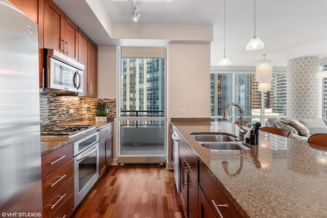 kitchen with decorative backsplash, appliances with stainless steel finishes, sink, decorative light fixtures, and stone counters