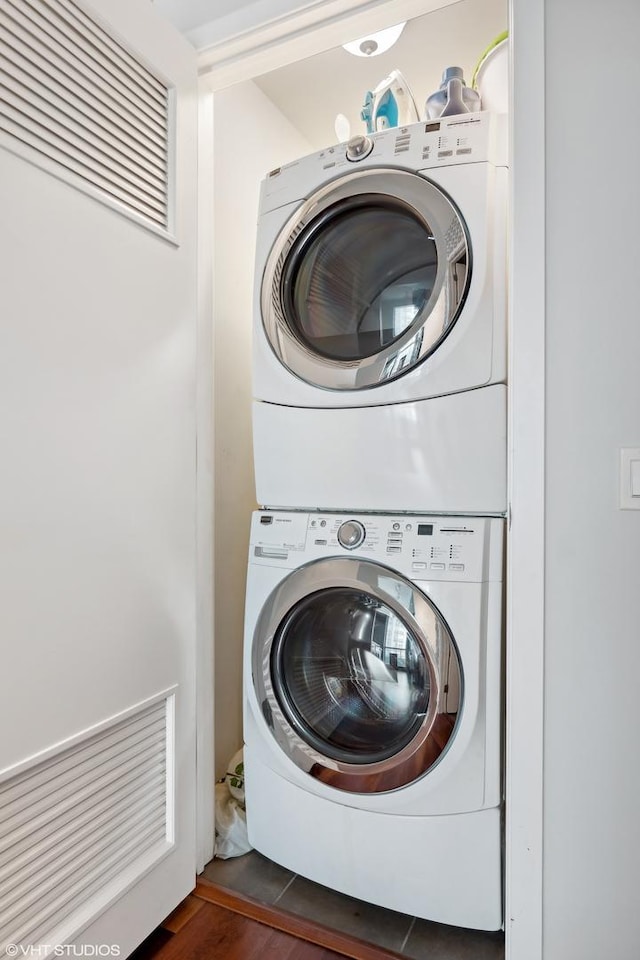 clothes washing area featuring stacked washer / dryer and dark wood-type flooring