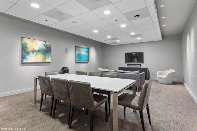 carpeted dining area featuring a paneled ceiling