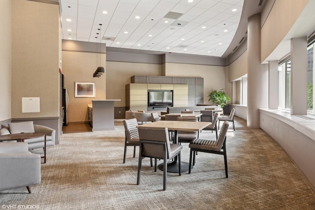 carpeted dining area featuring a high ceiling