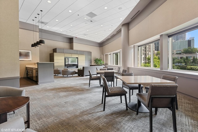 carpeted dining area featuring a high ceiling