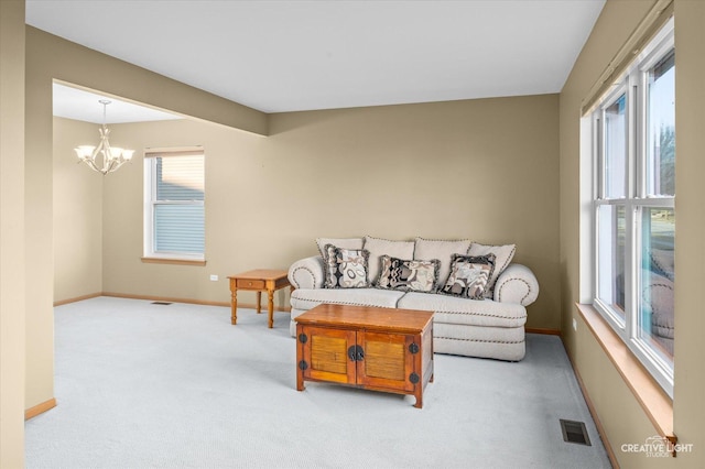 living room with a wealth of natural light, light carpet, and an inviting chandelier