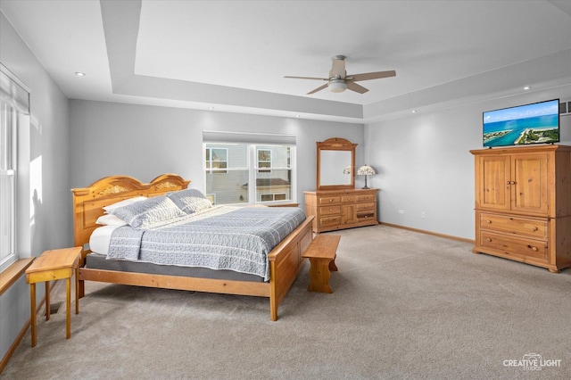 bedroom with carpet flooring, a raised ceiling, and ceiling fan