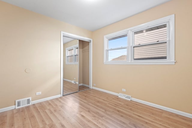 unfurnished bedroom with light hardwood / wood-style floors and two closets